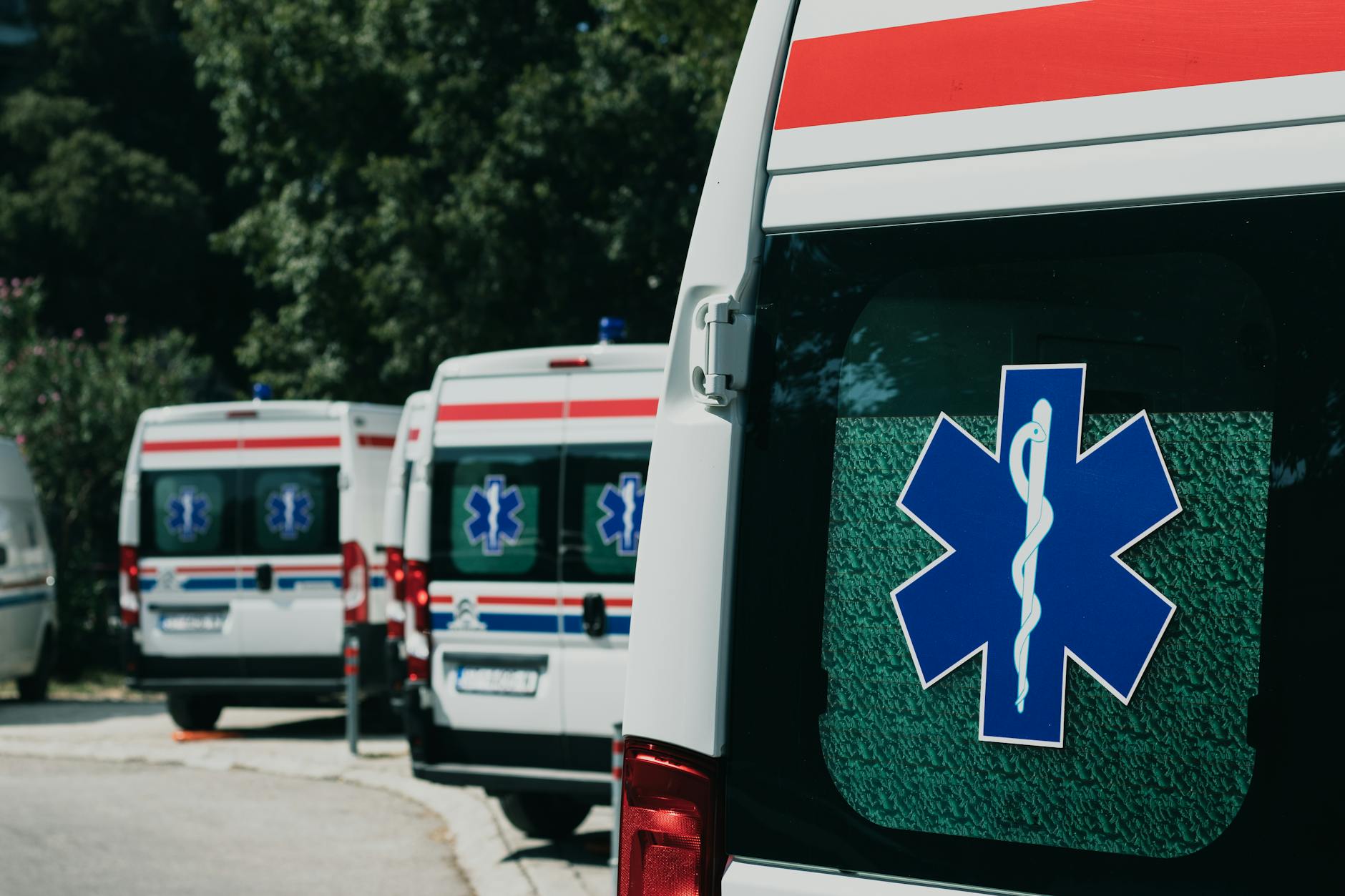 Varias ambulancias blancas estacionadas frente a un centro de salud en la ciudad.