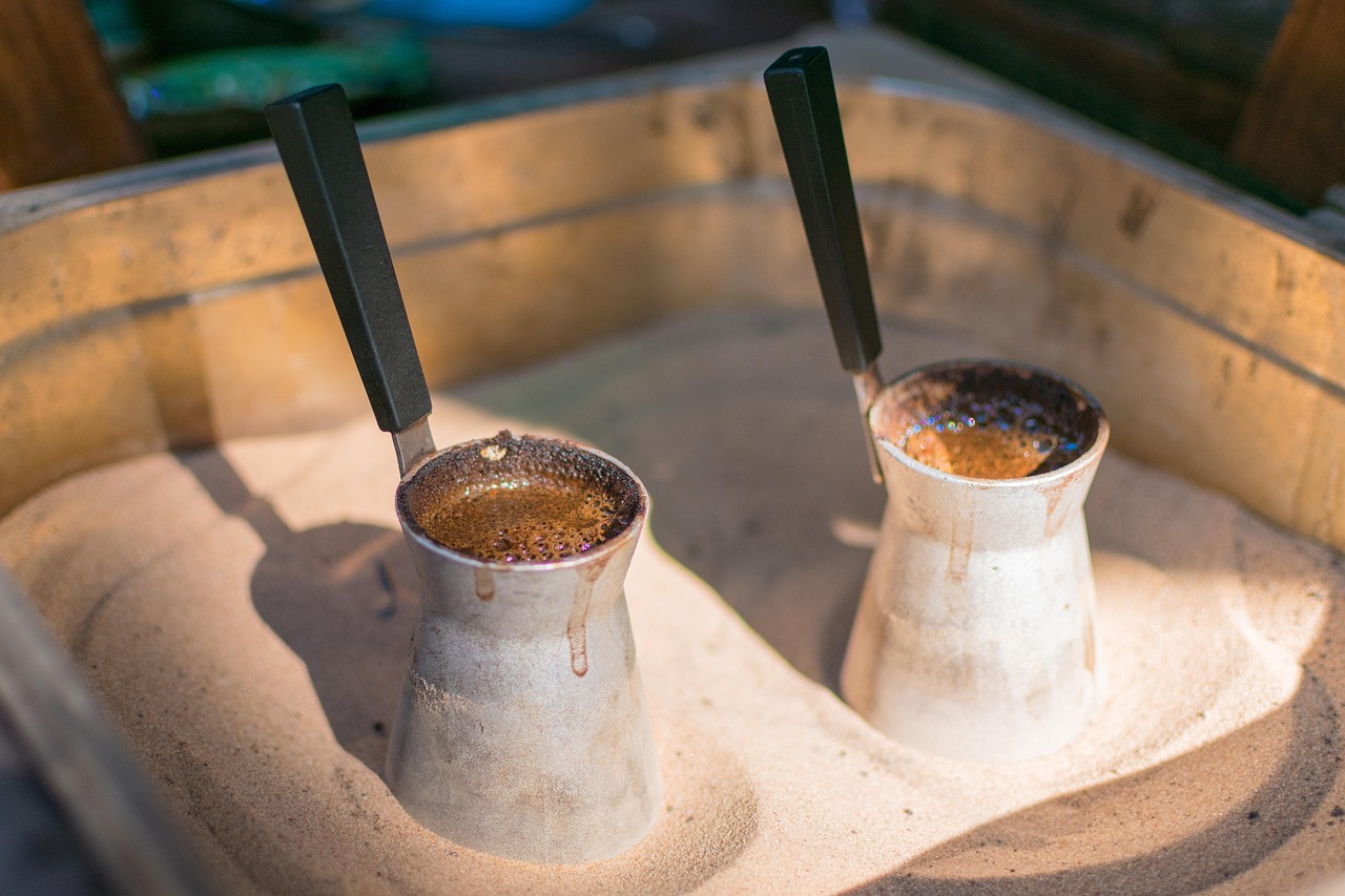 Proceso tradicional de elaboración de café turco sobre arena caliente en un puesto callejero.