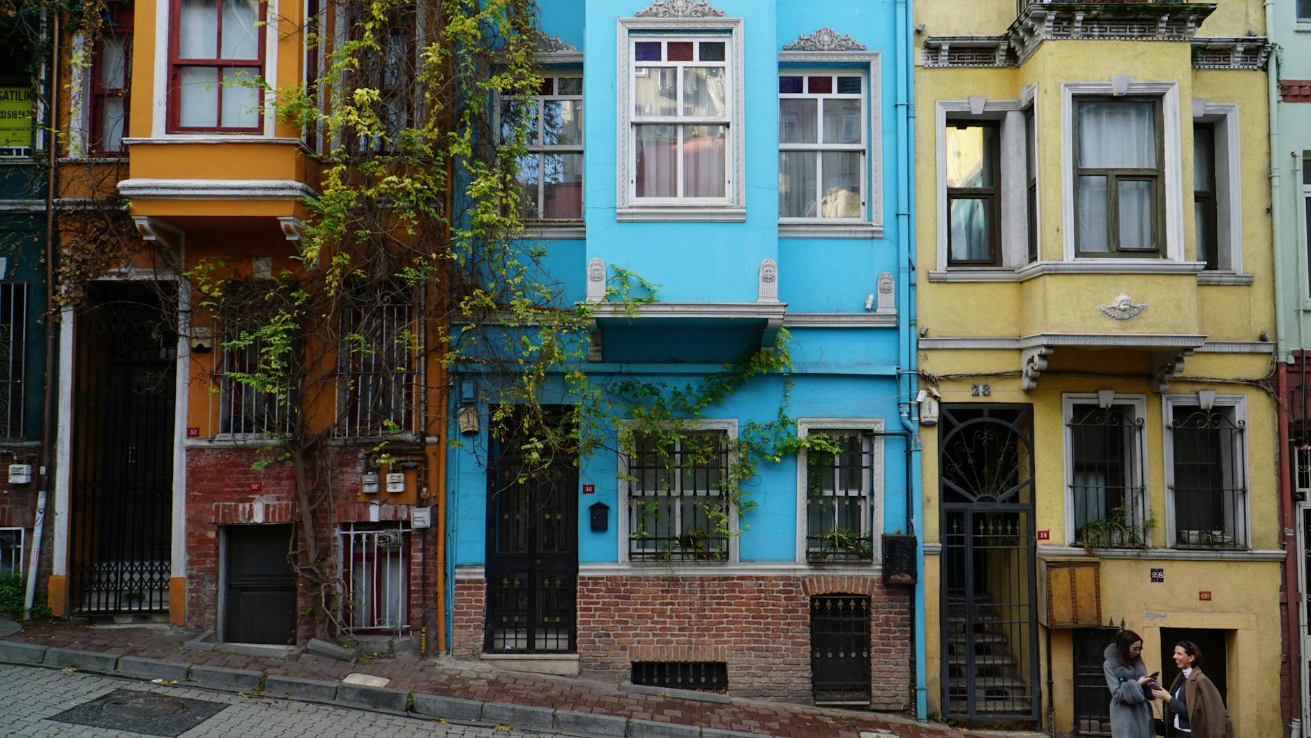 Casas tradicionales de colores brillantes en una calle empinada del barrio Kurtuluş.