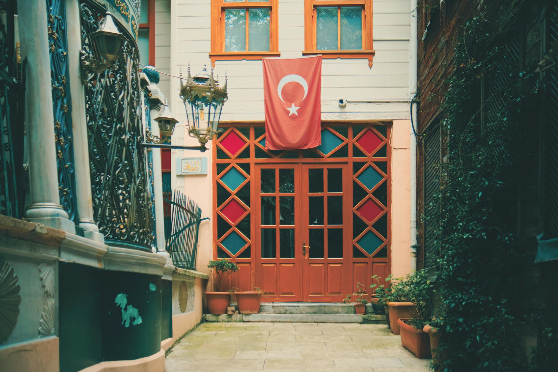 Puerta de acceso al museo Galata Mevlevihanesi con la bandera turca ondeando.