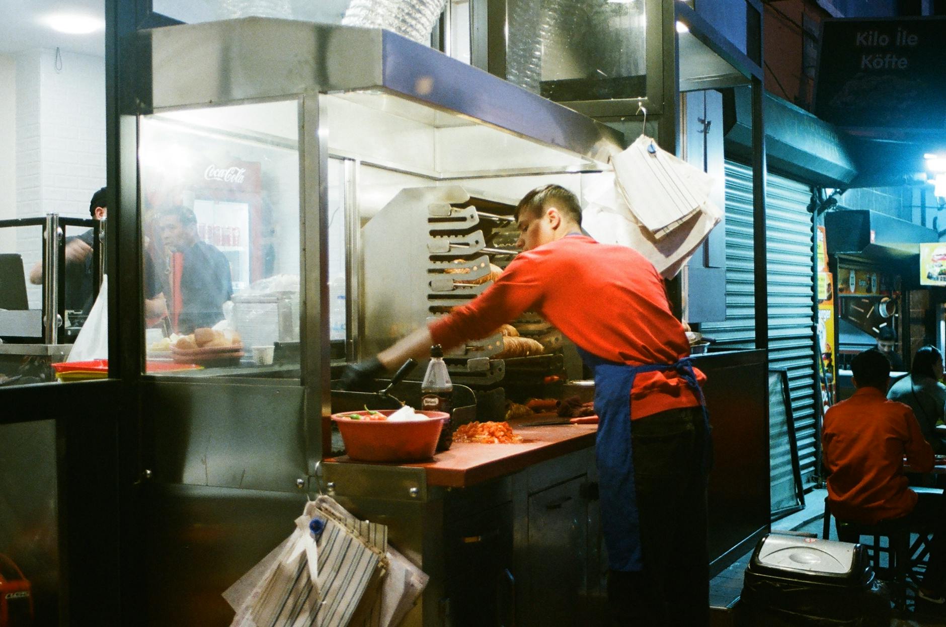 Cocinero preparando kokoreç tradicional en un puesto callejero típico de Estambul.
