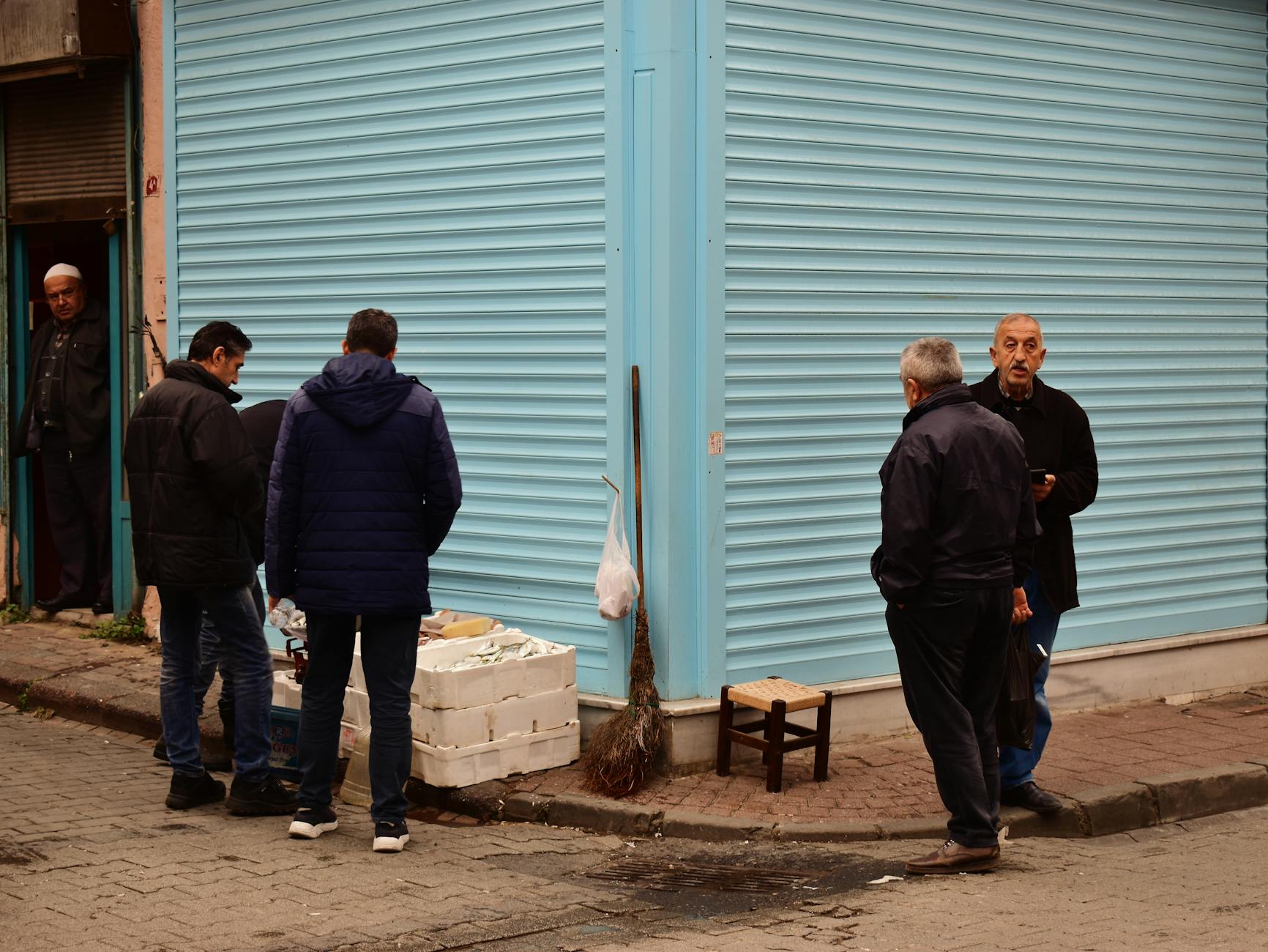 Vendedores locales y clientes frente a puestos de pescado fresco en una esquina de Kurtuluş.
