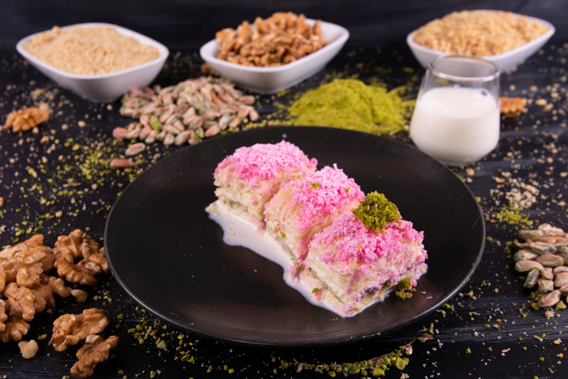 Postre de baklava frío con leche y pistachos servido en un plato negro elegante.