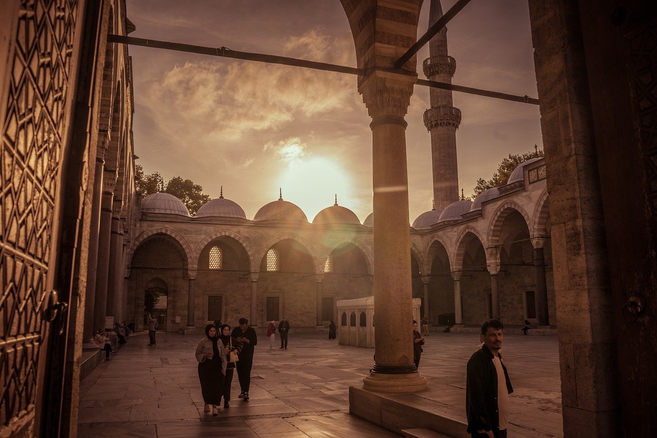 Visitantes caminando por el patio de una mezquita de Estambul durante el atardecer.