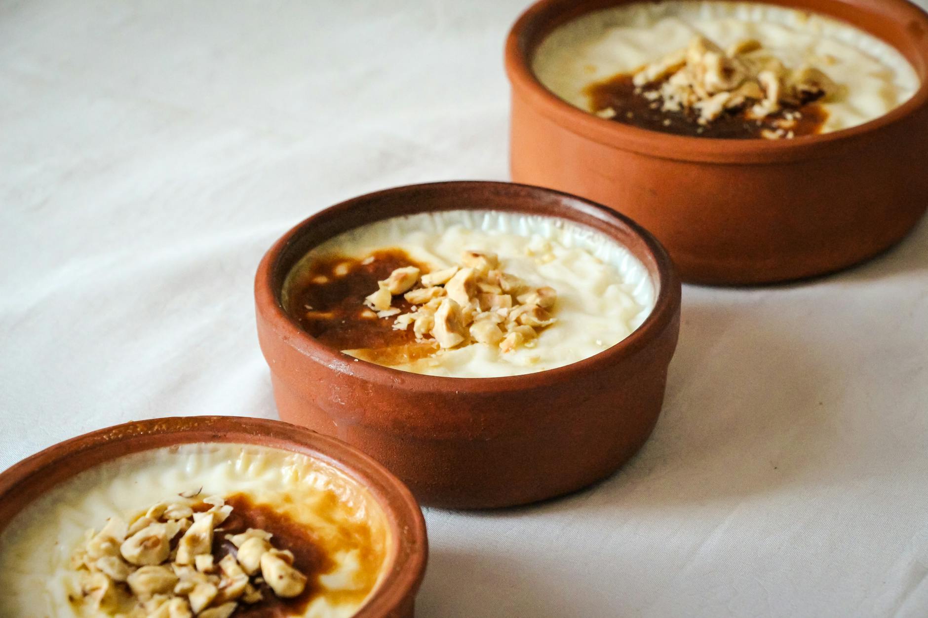 Recipientes de barro con arroz con leche turco tradicional decorados con avellanas picadas.